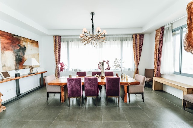 a spacious dining room with a modern rustic chandelier is lit bu natural light filtered through gauzy white curtains in the centre of the room is a large square wooded table surrounded by purple and beige fabric covered chairs